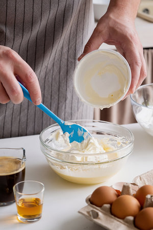 man wearing apron cooking tiramisu at kitchen. tiramisu cooking process