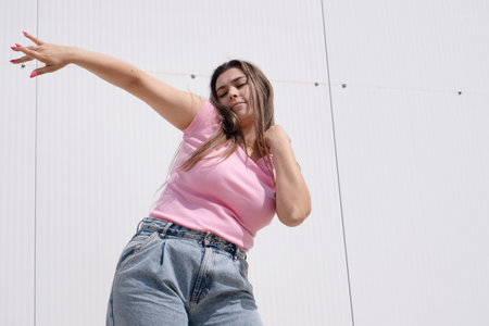 plus size woman wearing casual clothes dancing on white wall background in the street , leisure and funの写真素材