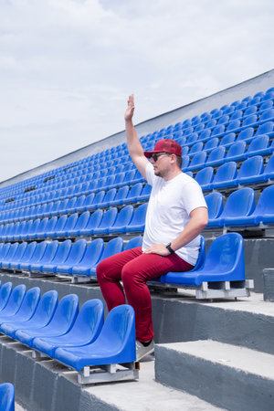 sportsman wearing red sports clothes with a bottle of water sitting and resting at the seats at the stadiumの写真素材