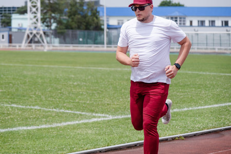 sportsman wearing read and white sport clothes running in the stadium