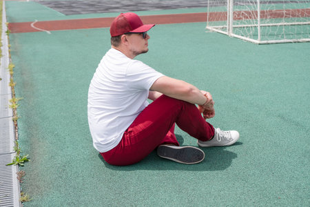Young man tired during jogging on the track in sport stadium. Young male intense training workout challenge feeling exhaustedの写真素材