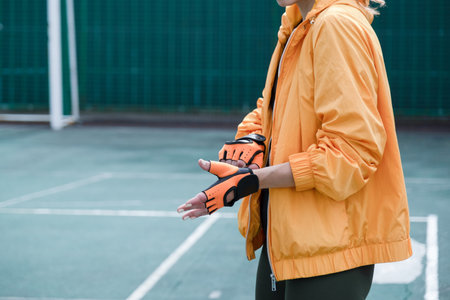 young female boxer in sports clothes training in the stadium putting on glovesの写真素材