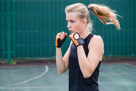 young sportive blond female boxer training, ready to punchの写真素材
