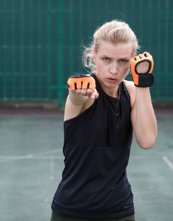 young sportive blond female boxer training, ready to punchの写真素材