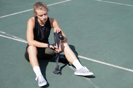 young sportive blond female boxer training, tying up wrist wrapsの写真素材