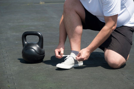 Sportive man workout with kettlebell outdoor in spring or summer