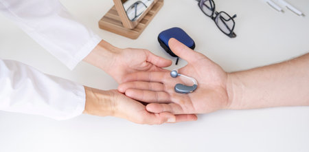 young male patient testing hearing aid in clinic exam room, young female doctor helpingの写真素材