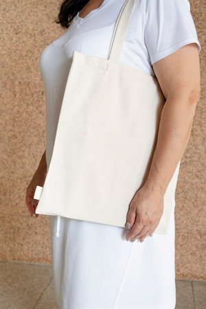 Blank white tote bag canvas fabric with mock handle up design. Close up of woman holding eco or...