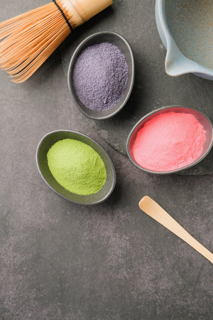 assortment of various powder matcha tea, pink, blue and green. closeup os green matcha bowl