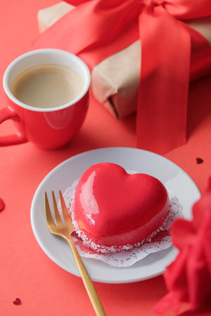 Valentines day or birthday greeting card. red heart cake on small plate and coffee for valentines day, red backgroundの写真素材