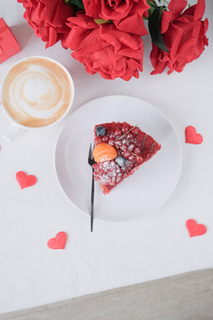 Valentines day or birthday background. red velvet cake with fruit and coffee for valentines day, decorations and confetti on white table setting, copy spaceの写真素材