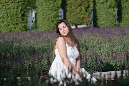 pretty young woman in white dress sitting at the sage flower field. spring blossomの写真素材