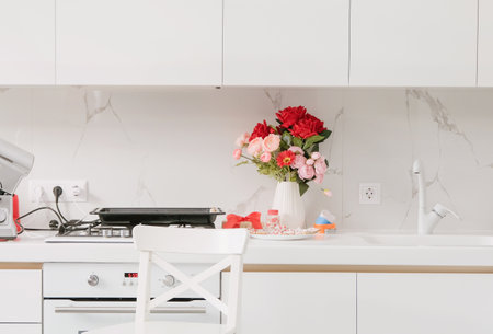 Red flowers, white counters and stylish decor for Valentine's Day celebration in kitchen interiorの写真素材