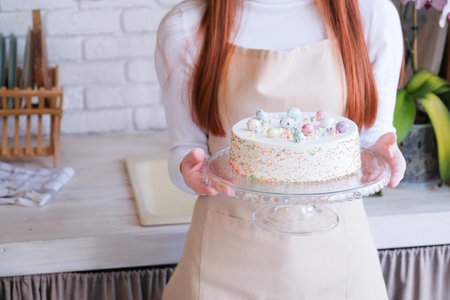 Happy Easter. woman holding Easter cake in pastel colors in the kitchen, getting ready for holiday