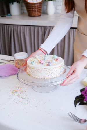 Happy Easter. cropped shot of woman holding Easter cake in pastel colors in the kitchen, getting...