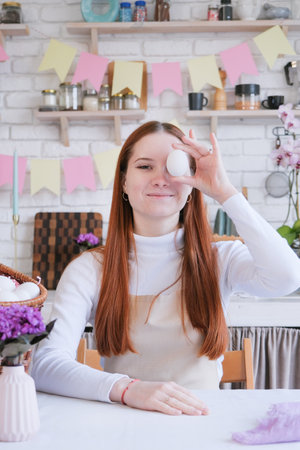 Easter Family traditions. woman in apron coloring white easter eggs, covering eyes and smiling