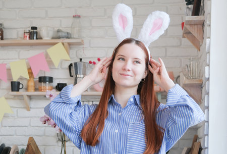 Caucasian woman in bunny ears standing by serving table for Easter dinnerの写真素材