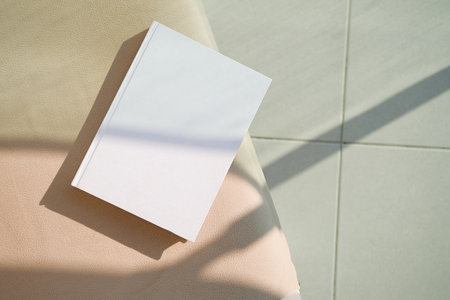 book cover mockup design. blank book template on soft beige armchair on terrace or balcony, shadow overlayの写真素材