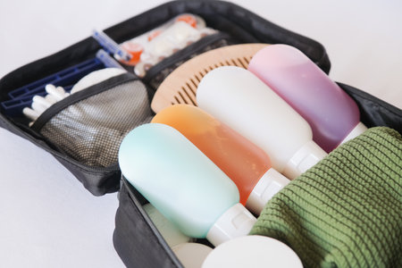 Black cosmetic travel kit on the bed. colorful cosmetic bottles, pills and hygiene items for travelの写真素材