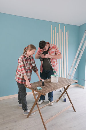 Happy couple renovating new house apartment painting wood boards together. Home makeover, renovation concept. Family man woman repair flat themselves.の写真素材