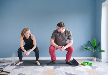 couple training at home squatting together, lifestyle and sports conceptの写真素材
