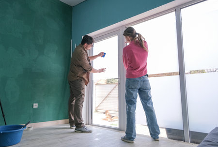 a couple tinting windows and doors glass at home using toning film and levelの写真素材