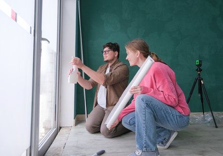 a couple tinting windows and doors glass at home using toning film and level