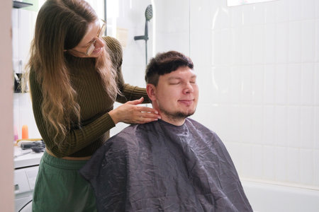 young caucasian woman cutting man hair in bathroom at home , smilingの写真素材