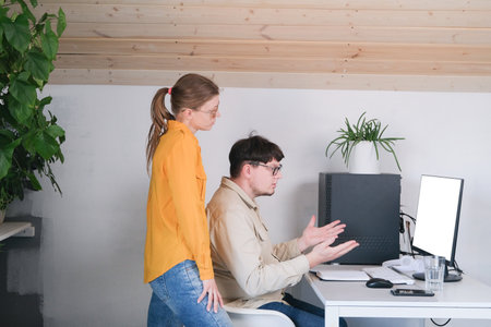 millennial man and woman in casual clothes using and computer while spending time at home, watching funny videosの写真素材