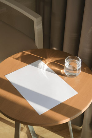 paper poster cover mockup design. blank paper poster mockup on round wooden coffee table with glass...