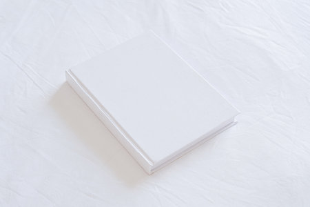 White book hardcover mockup on white bed