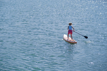 woman rowing sup board on sea water , paddleboard and surfing, beautiful gleaming and glittering...