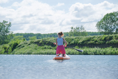 woman rowing sup board on river water adjusting the paddle , paddleboard and surfing, trending sports and hobbyの写真素材
