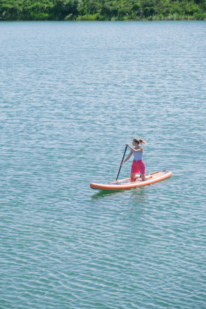 woman rowing sup board on river water , paddleboard and surfing, trending sports and hobby