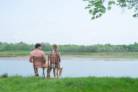 Family on picnic near the lake, sitting on chairs, looking at viewの写真素材