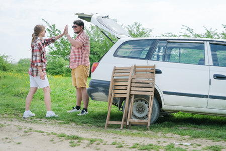 Family on picnic, gathering table and chairs into the car