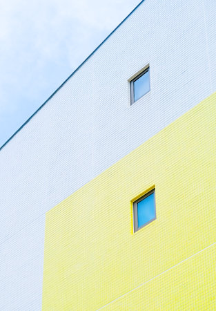 small square window on yellow bright exterior tiled wallの写真素材