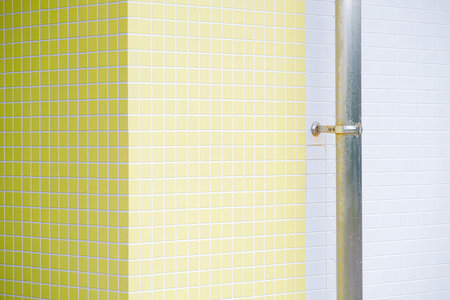 Yellow and white tiled wall with a metal pipe