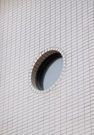small round window on bright exterior tiled wall