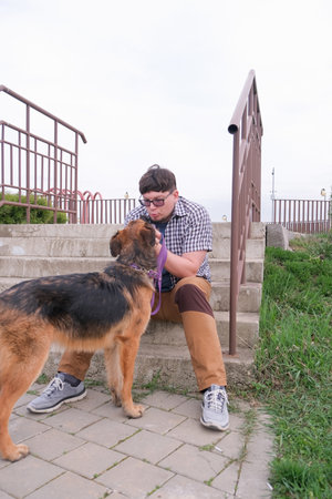 Man walking his dog, stroking it sitting in the grass in the park. Dogの写真素材