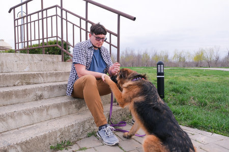 Man walking his dog, stroking it sitting on the stairs in the park. Dogの写真素材