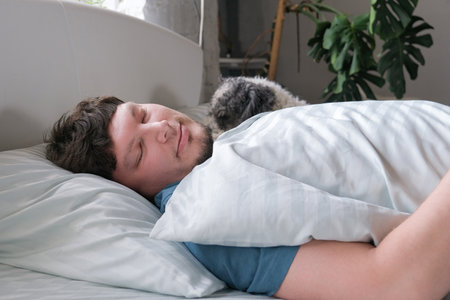 life with pets. Young millennial man sleeping lying in the bed in the morning with dogs