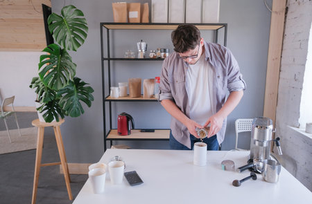 young millennial man grinding coffee at home, making coffee in the morningの写真素材
