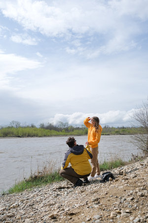 young couple in love enjoying the beautiful nature in early spring near riverside huggingの写真素材