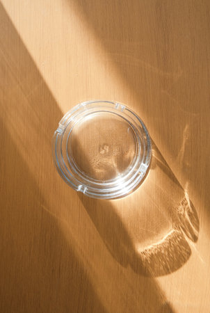 Glass tray on brown wooden table with shadow, top viewの写真素材