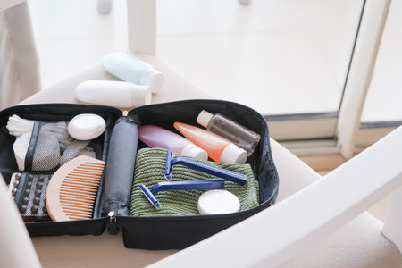 Black cosmetic travel kit on the soft chair. colorful cosmetic bottles, pills and hygiene items for travelの写真素材