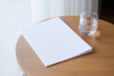 blank magazine mockup on round wooden coffee table with glass of water in the roomの写真素材
