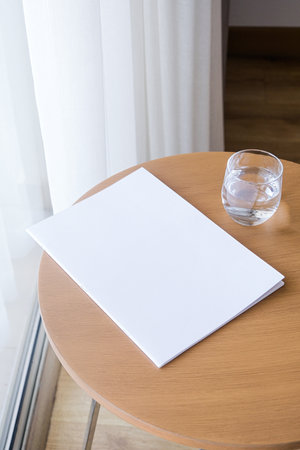 blank magazine mockup on round wooden coffee table with glass of water