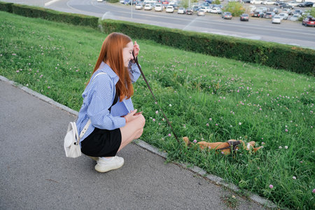 two female friends walking their dog in the city streetの写真素材
