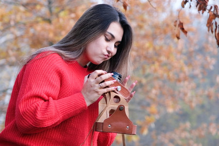Portrait of a photographer with the vintage camera, taking a picture in autumn forest, upset with...